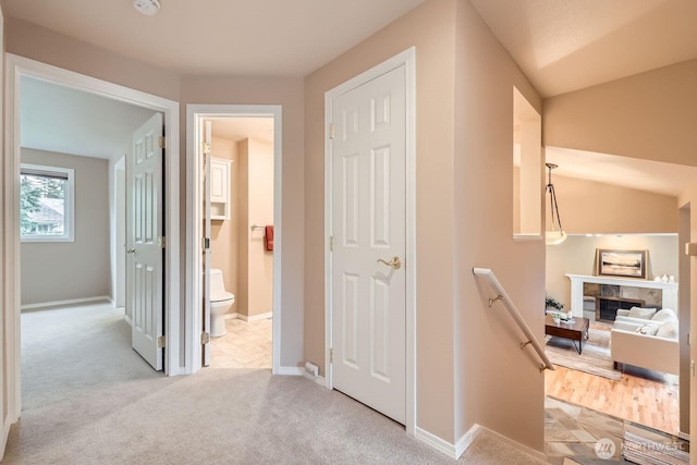 corridor with baseboards, light carpet, and an upstairs landing