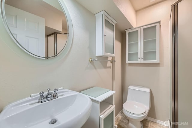 bathroom with baseboards, a sink, and toilet