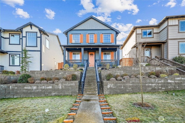 view of front of home with covered porch, stairs, and a front yard