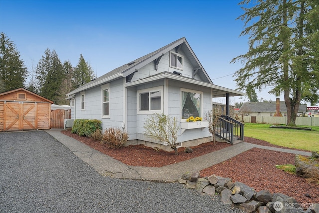 view of front of home with central air condition unit, a front yard, fence, and an outbuilding