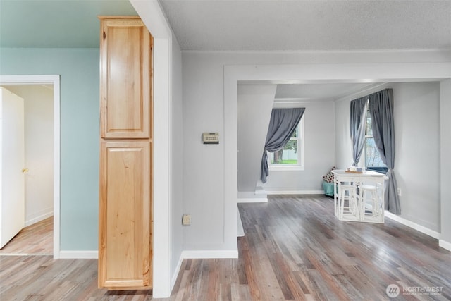 corridor featuring a textured ceiling, baseboards, and wood finished floors