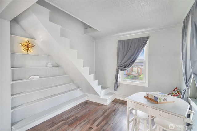 stairway featuring a textured ceiling, baseboards, and wood finished floors