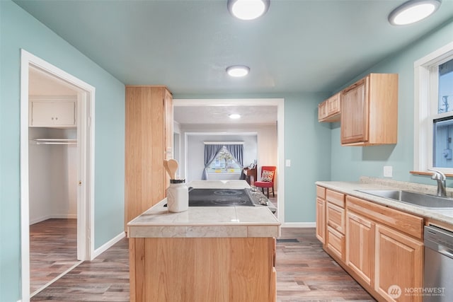 kitchen with dishwasher, a sink, light wood-style flooring, and light brown cabinets