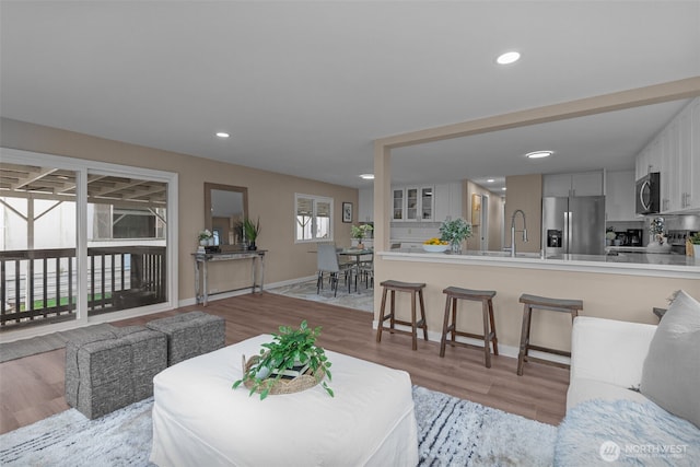 living room featuring light wood-style floors, baseboards, and recessed lighting