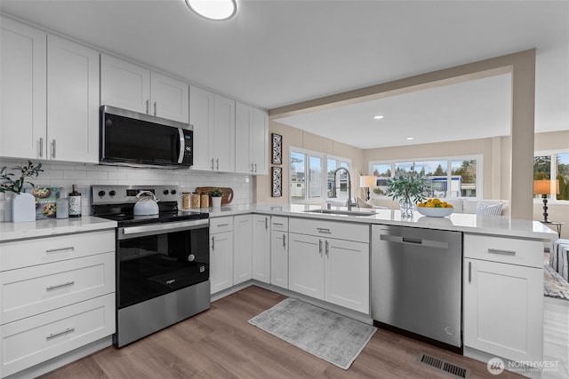 kitchen featuring visible vents, appliances with stainless steel finishes, white cabinets, and a sink
