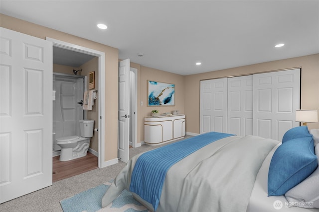 bedroom featuring connected bathroom, light colored carpet, recessed lighting, baseboards, and a closet