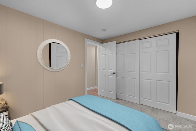 carpeted bedroom featuring baseboards and a closet