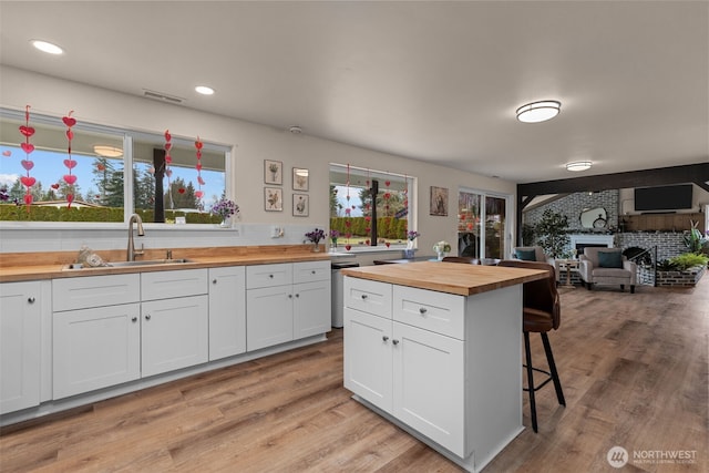 kitchen featuring a sink, white cabinetry, a kitchen breakfast bar, open floor plan, and wooden counters