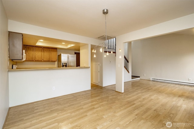 unfurnished living room featuring light wood finished floors, visible vents, stairway, a tray ceiling, and baseboard heating