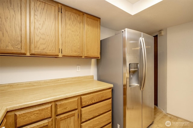 kitchen with light wood-type flooring, light countertops, and stainless steel refrigerator with ice dispenser