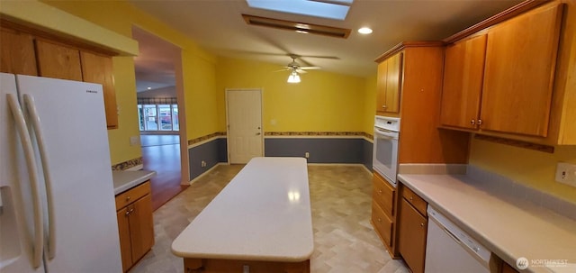 kitchen featuring light countertops, brown cabinetry, vaulted ceiling, ceiling fan, and white appliances