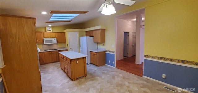 kitchen with brown cabinetry, white appliances, light countertops, and a kitchen island