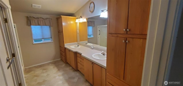 bathroom featuring double vanity, a sink, visible vents, and baseboards