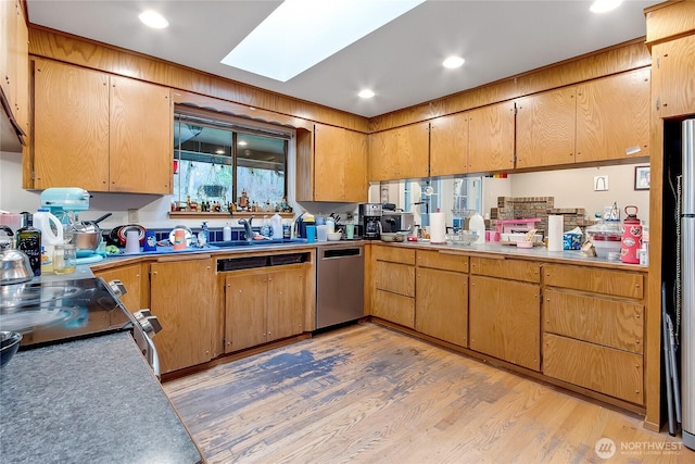 kitchen featuring a skylight, recessed lighting, a sink, light wood-type flooring, and dishwasher