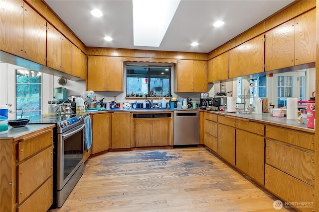 kitchen featuring appliances with stainless steel finishes, a skylight, and brown cabinetry