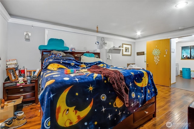 bedroom with ornamental molding and wood finished floors