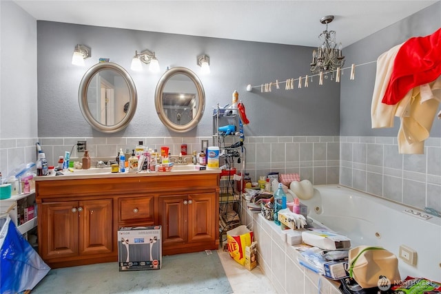 full bathroom featuring a notable chandelier, a tub with jets, and double vanity