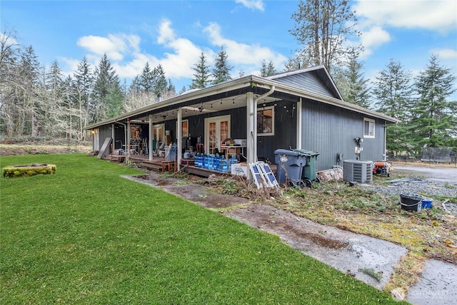 back of house featuring cooling unit, french doors, and a lawn