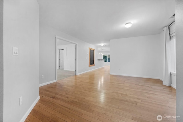 unfurnished room with baseboards and light wood finished floors