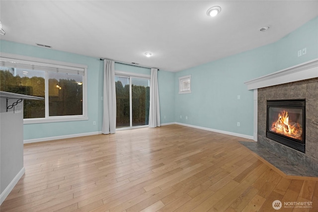 unfurnished living room featuring visible vents, a fireplace, baseboards, and wood finished floors