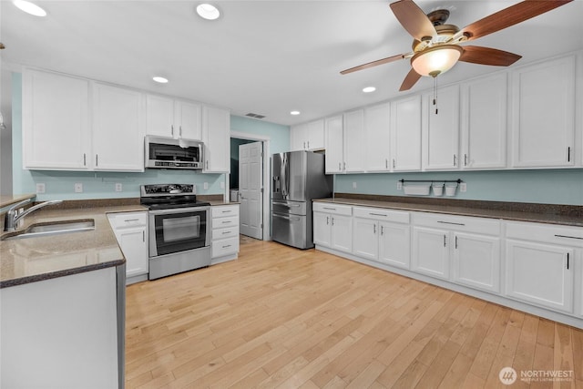 kitchen featuring recessed lighting, appliances with stainless steel finishes, white cabinetry, a sink, and light wood-type flooring