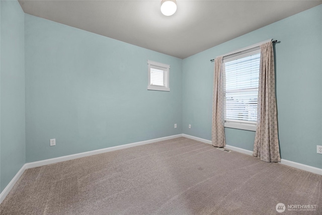 empty room featuring carpet, visible vents, and baseboards