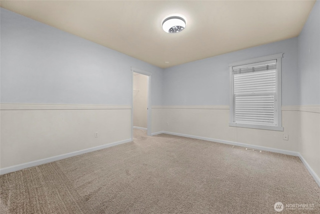 empty room featuring carpet floors, visible vents, and baseboards