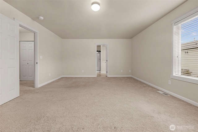 spare room featuring baseboards, visible vents, and light colored carpet