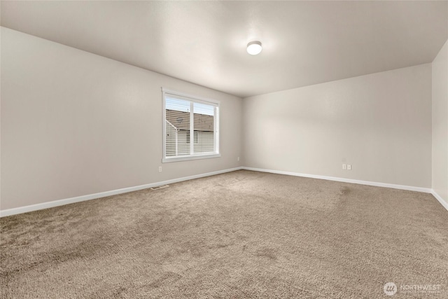 spare room featuring carpet, visible vents, and baseboards