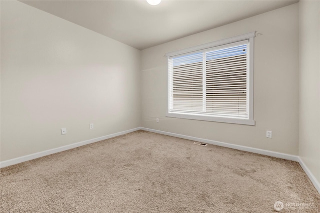 spare room featuring carpet, visible vents, and baseboards