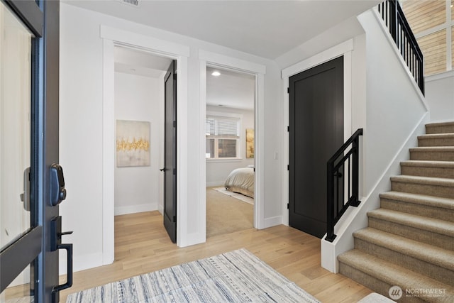 foyer with light wood-type flooring, baseboards, and stairs
