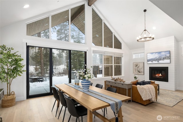 sunroom with lofted ceiling, a large fireplace, and a notable chandelier