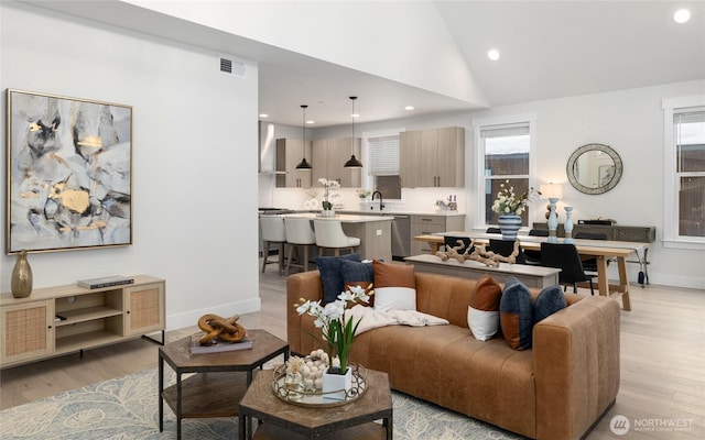 living area featuring lofted ceiling, recessed lighting, visible vents, light wood-style flooring, and baseboards