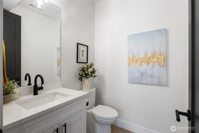 bathroom with visible vents, vanity, toilet, and baseboards