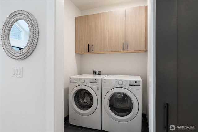 clothes washing area with cabinet space, washing machine and dryer, and dark tile patterned flooring