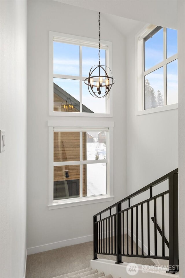 staircase with carpet flooring, baseboards, and an inviting chandelier