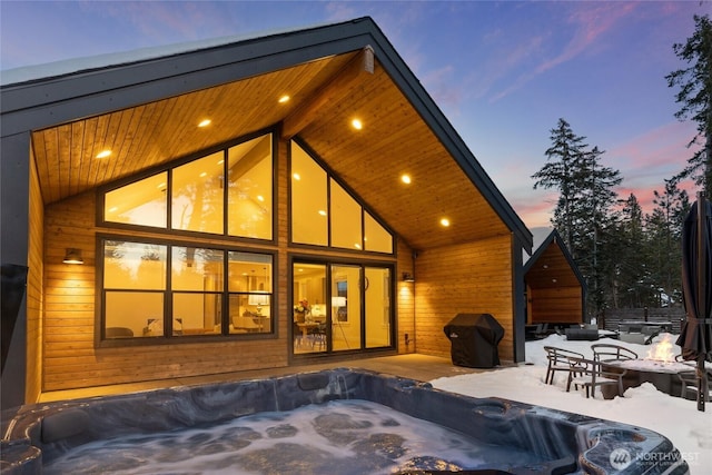 back of property at dusk featuring a patio and a hot tub