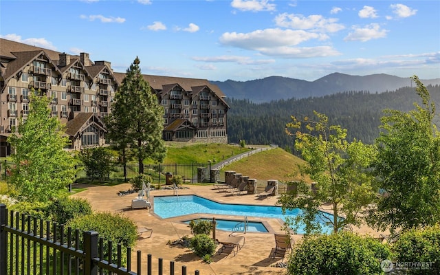 pool with a patio area, fence, and a mountain view