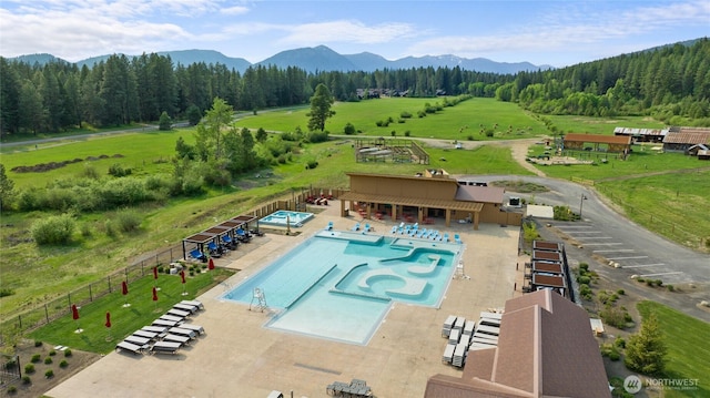 pool with a hot tub, a rural view, fence, a patio area, and a mountain view