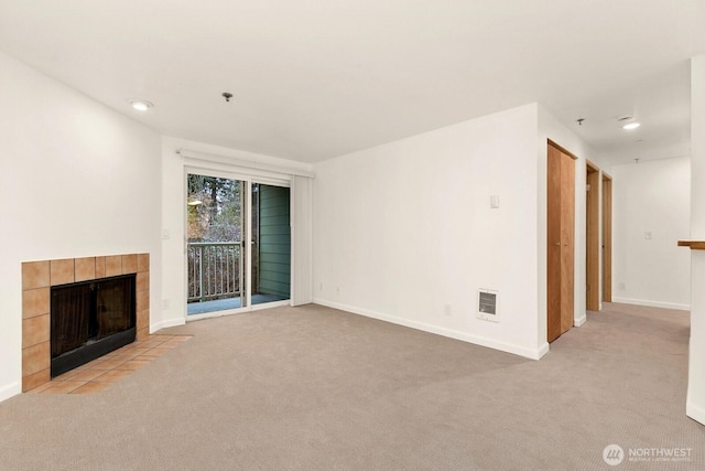 unfurnished living room with a tile fireplace, recessed lighting, light colored carpet, visible vents, and baseboards