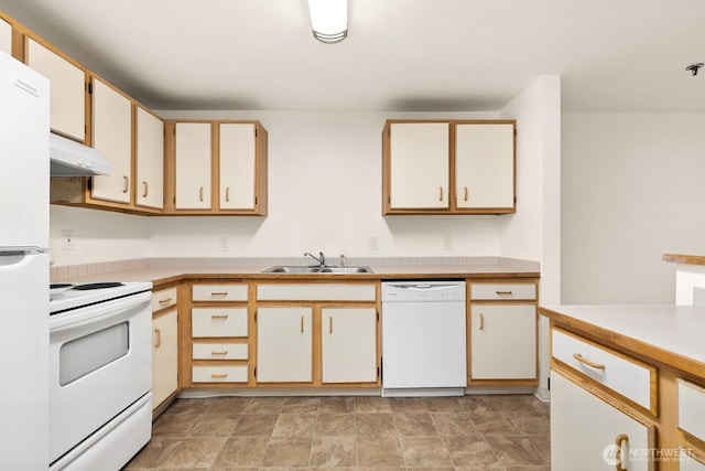 kitchen with white appliances, under cabinet range hood, light countertops, and a sink