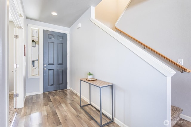 entrance foyer with light wood-type flooring, baseboards, and stairway