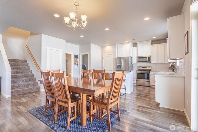 dining area featuring baseboards, stairway, wood finished floors, a chandelier, and recessed lighting