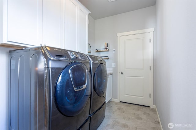 washroom with cabinet space, baseboards, and washer and dryer