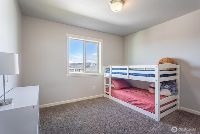 bedroom with dark colored carpet, a textured ceiling, and baseboards