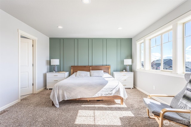 bedroom with light carpet, baseboards, a decorative wall, and recessed lighting