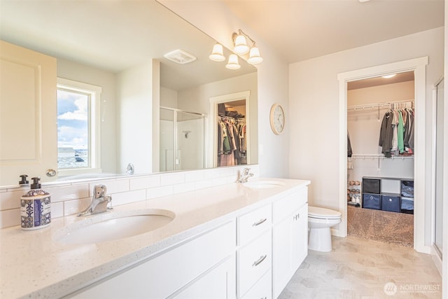 bathroom featuring double vanity, a stall shower, toilet, and a sink