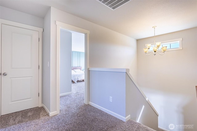 corridor with visible vents, baseboards, light colored carpet, an upstairs landing, and a notable chandelier