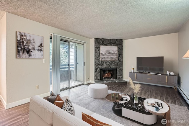 living area featuring a fireplace, a textured ceiling, baseboards, and wood finished floors