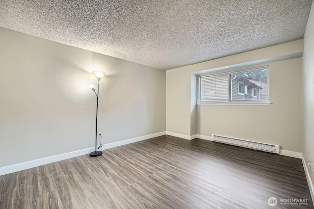 empty room with a textured ceiling, a baseboard radiator, wood finished floors, and baseboards